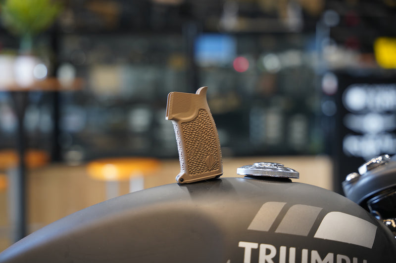 Load image into Gallery viewer, A grip for an airsoft gun motor placed on top of a motorcycle tank with a blurred background.
